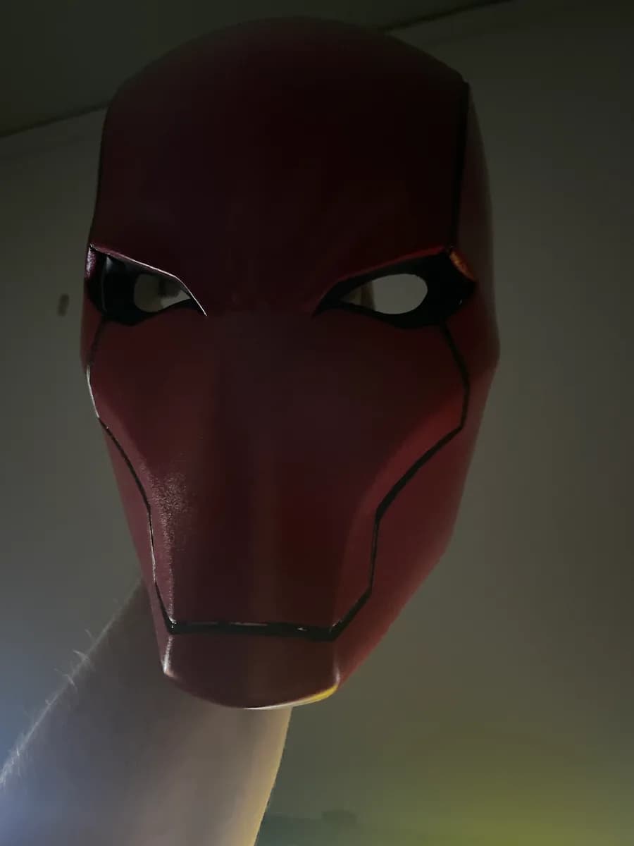 Röd cosplaymask med svarta konturer sedd framifrån
